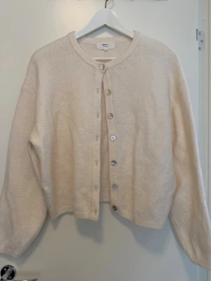 Beige kofta från Ginatricot - Mysig beige kofta från Ginatricot med rund halsringning och knappar framtill. Koftan är använd 1 gång men jag tycker att den ”fäller”. Inga fler bilder skickas då den ligger i flyttlåda.