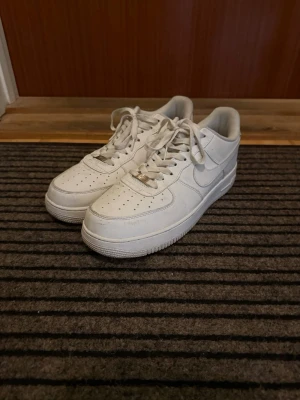 Nike Air Force 1 (VET EJ OM DE ÄR ÄKTA) - Klassiska vita Nike Air Force 1 sneakers i läder med perforerad tå, vit sula och ikonisk Swoosh på sidan. Skorna har lågt skaft och vita skosnören. Perfekta för en clean och stilren look. (FICK DESSA SKOR SÅ ÄR OSÄKER PÅ OM DE ÄR ÄKTA ELLER EJ) 