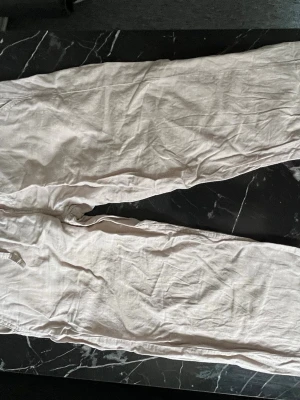 linnebyxor från Jack & Jones - Säljer ett par beiga linnebyxor från Jack & Jones. Byxorna har rak passform och resår i midjan för extra komfort. Perfekta för en avslappnad och stilren look. Materialet är svalt och luftigt linne.