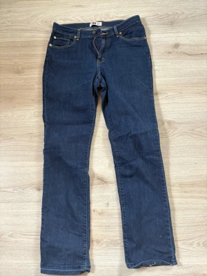 Mörkblå raka jeans från 304 - Snygga mörkblå jeans från 304 med klassisk femficksdesign och raka ben. Jeansen har guldfärgade nitar och kontrastsömmar. Tillverkade i denim med en tidlös look som passar till det mesta.