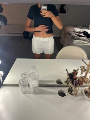 Vita höga shorts med resårmidja - Säljer ett par vita shorts med hög midja och resår i midjan. De är enkla och stilrena, perfekta för varma dagar. Shortsen har en loose passform och är gjorda i ett lätt och bekvämt material.