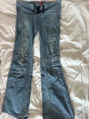 Blå bootcut jeans med snörning - Snygga blå bootcut jeans från miss sixty med cool snörning i midjan. Jeansen har markerade sömmar och lätt utsvängda ben, vilket ger en retro vibe. Perfekta för dig som gillar en avslappnad men trendig stil.