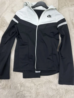Nike svart och vit tracksuit - Nike vindjacka och matchande byxa. Säljer för de är för små