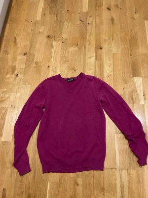 Vinröd v-ringad stickadtröja Redwood stl S - Snygg stickad vinröd  tröja från Redwood med v-ringning och långa ärmar. Tröjan har en klassisk passform och är tillverkad i ett mjukt material som känns skönt mot huden. Perfekt för lager-på-lager och enkel att matcha med jeans eller kjol.