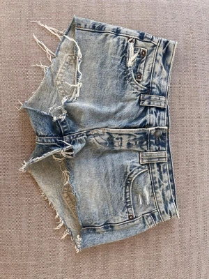 Blå jeansshorts med fransig kant - Säljer ett par blå jeansshorts med fransig kant och slitna detaljer. Köpta på zalando men är från pull and bear. Tror att dem kostade 300 nypris. Storlek: 36. Midjemått tvärs över 39 cm. Bara att skriva om du har några frågor🤗🤗