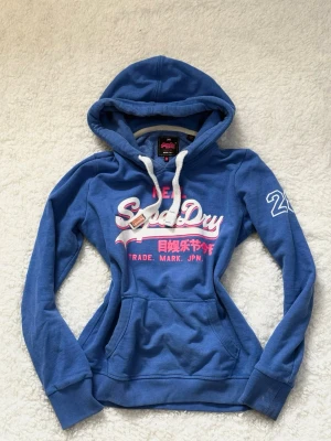 Blå hoodie från Superdry  - Blå hoodie från Superdry med vit och rosa logga 