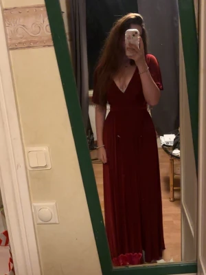 Vinröd balklänning med v-ringning - Säljer en elegant vinröd balklänning med djup v-ringning och korta ärmar. Klänningen har ett markerat midjeband och ett flödande fall som ger en snygg siluett. Perfekt för dig som vill ha en stilren och klassisk look. xs-s storlek