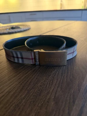 Rutmönstrat Burberry bälte i skinn - Säljer nu detta fina bälte från burberry, köpt sommaren 2023 i Mallorca för 4299kr. Har tyvärr inget äkthetsbevis på bälte, vilket är varför jag säljer det så billigt. Skriv om ni har några frågor! :)