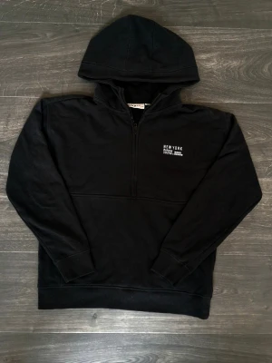 Svart hoodie med halv dragkedja - Svart hoodie från New Yorker med halv dragkedja. Stilren och bekväm hoodie som är lätt att matcha. Passar bra till vardag. Storlek: 164