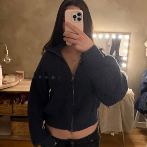 Mörkblå stickad ziptröja - Mysig mörkblå stickad tröja med dragkedja framtill och hög krage. Den har dragkedja åt båda hållen så den går att styla på många sätt. Jätte mysig och fluffig. Säljer då den inte kommer till användning.