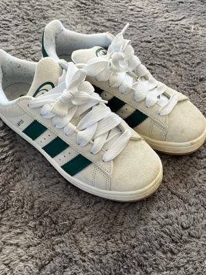 Adidas Campus vita/gröna sneakers - Snygga Adidas Campus sneakers. Storlek 40, Använda ca 2 gånger. Det finns lite smuts men det går lätt bort med lite vatten. Nypris 1299kr mitt pris 850kr