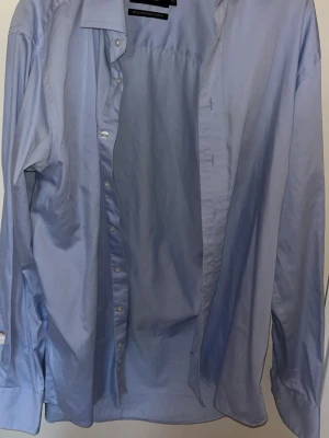 Ljusblå skjorta från Dressman - Klassisk ljusblå skjorta från Dressman med lång ärm och knappar framtill. Skjortan har en stilren krage och är tillverkad i ett tunt, mjukt bomullstyg som känns skönt mot huden. Perfekt för dig som gillar en clean och tidlös look.      |Nypris 799kr|