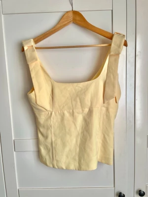 Ljusgul linnetopp med rosett band  - Supersöt ljusgul topp från Zara med breda rosett axelband och fyrkantig urringning. Toppen har en clean, minimalistisk look som passar perfekt till sommaren. Passar även storlek S. 