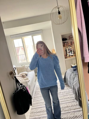 Blå stickad tröja med puffärm - Snygg blå stickad tröja med puffade axlar och rund halsringning. Tröjan har långa ärmar och ribbade muddar vid ärmslut och nederkant. Perfekt för att ge din outfit en trendig touch. Mjukt och skönt material!💗💕💞