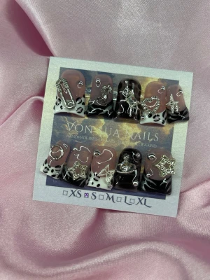 Yua (S); Medium Duck Nails - Unika handgjorda duck press-on naglar i svart och nude med coola silverdetaljer som stjärnor och säkerhetsnål. Naglarna har leo print och 3D-metallaccessoarer för en edgy look. Perfekt för dig som vill sticka ut med trendiga och kreativa naglar.S: 15 mm, 11,5 mm, 12 mm, 11 mm, 9 mm 