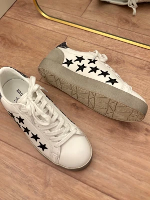 Vita svart grå silver glitter skor sneakers stockholmsstil trendy trendig populär stjärna detaljer - Trendiga skor i storlek 37. Endast använd en gång, som i nyskick! Köpt utomlands på butiken Brownie i Spanien – dyra vid inköp.