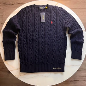 Polo Ralph Lauren Cable Knit Tröja  - Klassisk kabelstickad tröja från Polo Ralph Lauren i marinblå färg.  Mjuk och bekväm kvalitet med rund halsen. Passar grish stilen                                                                         Storlek M Skick 10/10 
