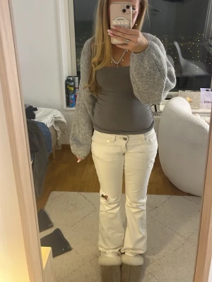 Grå stickad kofta med ballongärmar - Mysig grå stickad kofta med trendiga ballongärmar och öppen front. Perfekt att slänga över ett linne eller t-shirt för en avslappnad look. Koftan har en lös passform och är stickad i ett mjukt material.