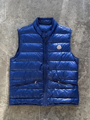 Moncler GUI väst - Säljer denna snygga moncler gui väst! | Storlek 4, passar medium | Skick: 7/10, lite skavanker, se bilder. Inget som syns vid användning | Pris: 1300kr ‼️ sjukt bra pris! | Garanterar alltid äkthet på alla våra varor.