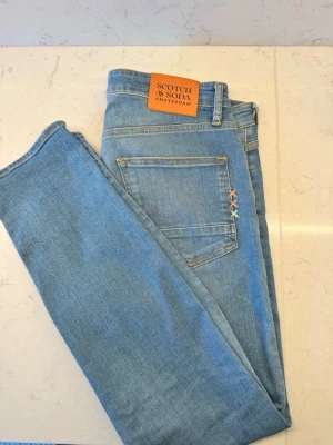 Ljusblå jeans från Scotch & Soda - Snygga ljusblå jeans från Scotch & Soda med. Jeansen har en rak passform och är tillverkade i mjuk denim. Storlek 31/32