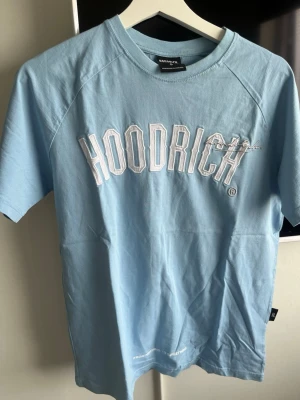 Ljusblå HOODRICH t-shirt - Snygg ljusblå t-shirt från HOODRICH med vit broderad logga framtill. Klassisk passform och rund halsringning. Perfekt för en avslappnad streetwear-look.