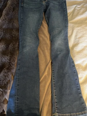 Blå bootcut jeans low waist - Snygga blå bootcut jeans med låg midja och slim fit. Klassisk denim med lätt slitning och utställda ben. Perfekta för dig som gillar retrostil och vill ha ett par jeans som sticker ut lite extra.