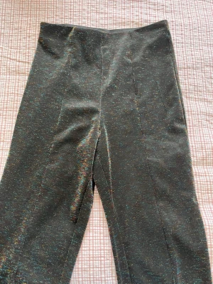 Svarta glittriga leggings med hög midja - Säljer ett par svarta leggings med glittriga inslag och hög midja. De har raka ben och är stretchiga, vilket gör dem bekväma och snygga. Perfekta för dig som vill sticka ut lite extra med en diskret men cool glittereffekt. Från Cubus i storlek 146. 