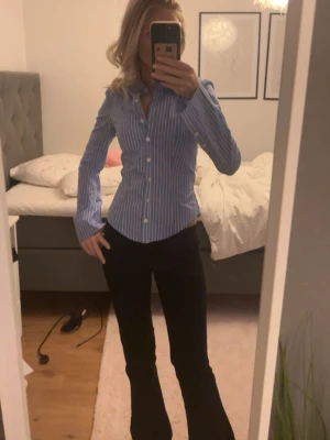 Blåvit randig skjorta - Snygg blå skjorta med vita ränder och klassisk krage. Skjortan har lång ärm och knäppning framtill. Figurnära passform som ger en stilren look. Perfekt för dig som gillar en klassisk men trendig stil. Använd en gång