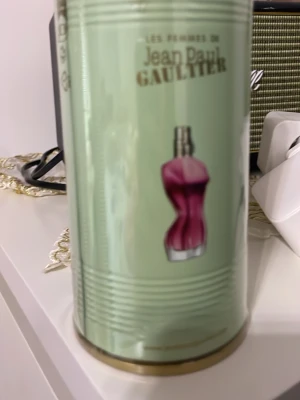 Jean Paul Gaultier La Belle parfym - Säljer en Jean Paul Gaultier La Belle Eau de Parfum. Parfymen kommer i en snygg ljusgrön metallburk med guldfärgade detaljer och logga. Flaskan har en ikonisk kvinnlig siluett i rödrosa glas. Perfekt för dig som gillar unika och lyxiga dofter.