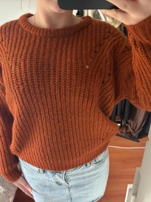 Rostbrun stickad tröja - Mysig rostbrun stickad tröja med grov ribbstickning och rund hals. Tröjan har en avslappnad passform och långa ärmar. Perfekt att styla med jeans eller kjol för en chill look.