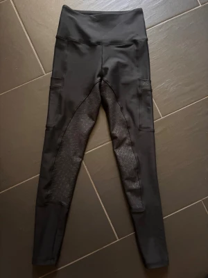 Svarta ridbyxor  - Säljer ett par svarta ridbyxor med hög midja och två sidofickor. Tillverkade i stretchigt material som sitter skönt och följer. Säljer pga för små för mig tyvärr. Använda en gång. 