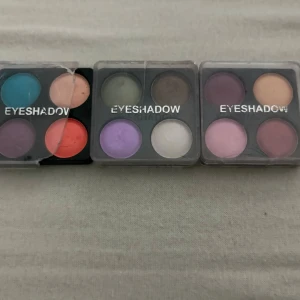 Ögonskuggspaletter i olika färger - Tre fyrkantiga ögonskuggspaletter med fyra nyanser i varje. Färgerna inkluderar blå, orange, lila, grön, brun, vit, rosa och beige. Paletterna har transparent lock och kompakt design. Perfekt för att skapa kreativa och färgstarka ögonmakeuper.