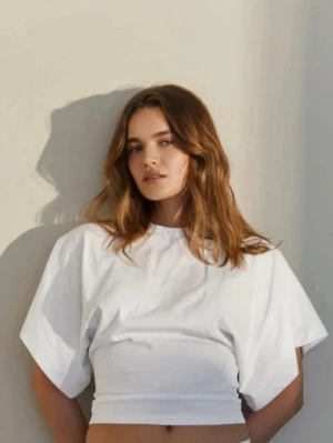 Vit t-shirt  - Säljer en vit croppad t-shirt med breda, korta ärmar och boxig passform. Toppen har rund halsringning och är gjord i ett mjukt bomullsliknande material. Perfekt för en avslappnad och trendig look. Från Avora!🤍