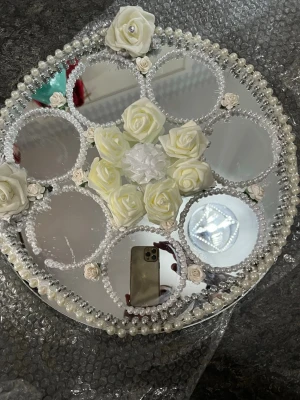 Dekorativ spegelbricka med pärlor och rosor - Rund spegelbricka dekorerad med vita konstgjorda rosor och pärlor. Spegeln har flera mindre speglar i cirklar, inramade av pärlband och små blommor. Perfekt som dekoration till bröllop, fest eller smyckesförvaring.