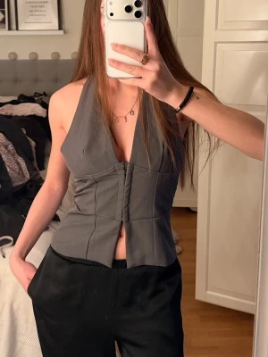 Grå korsett-topp med öppen rygg - Snygg grå korsett-topp med djup v-ringning och markerad midja. 