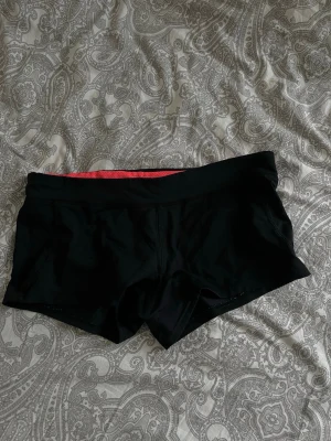 Svarta träningsshorts från Gina Tricot - Säljer ett par svarta träningsshorts från Gina Tricot med en snygg kontrastfärgad insida i rött