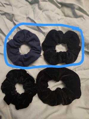 Fyra stycken scrunchies  - Säljer 4st hårsnoddar. Dem inringade är mörkblåa och dem andra är svarta. Alla har tvättats minst två gånger. Den sista bilden är på en av hårsnoddar som tydligen ska skydda från löss. 