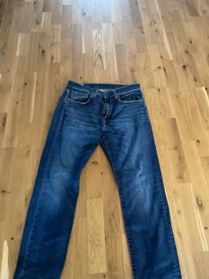 Levi's blå raka jeans 502 - Klassiska blå jeans från Levi's med rak passform och fem fickor. Jeansen har en snygg tvättad look och detaljer som bruna sömmar och läderpatch bak i midjan. Perfekta för en avslappnad stil och funkar till det mesta. Nypris ca1200. Pris kan diskuteras vid snabb affär. Fråga gärna vid funderingar. Storlek 31/30
