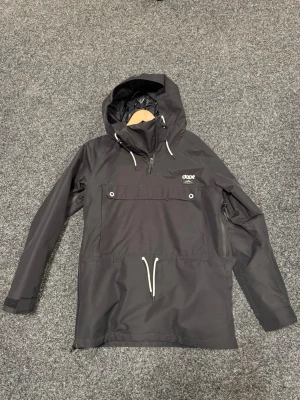 Svart skidjacka från Dope - Snygg svart skidjacka från Dope med stor magficka, dragkedjor i sidorna och justerbar huva. Jackan har vita snören och logga på bröstet. Perfekt för dig som vill ha en stilren och funktionell jacka med modern design i skidbacken. Endast provad en gång så helt ny.