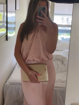 Ljusrosa  lång student/bal klänning med halterneck - Säljer nu min såå fina balklänning. Snygg unik design med halterneck och ganska öppen rygg. Jättefin ljusrosa färg! 