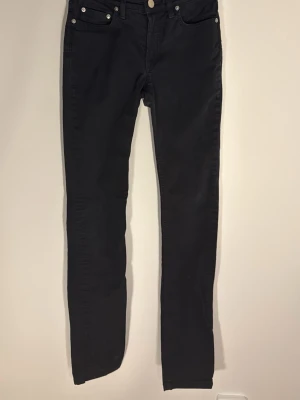 Svarta Gracie jeans från Filippa K i strl 27/32 - Snygga svarta Gracie Twill jeans från Filippa K med klassisk femficksmodell och smal passform. Tillverkade i 98% bomull och 2% lycra för en bekväm stretch. Perfekta för dig som gillar stilrena och tidlösa jeans.