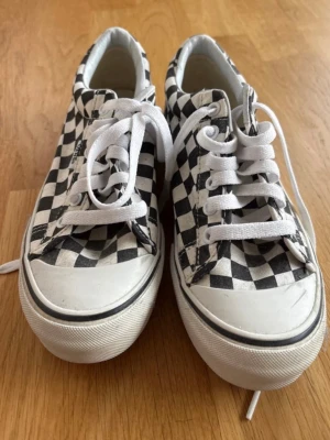 Vans checkerboard låga sneakers i strl 37 - Klassiska Vans sneakers med svartvitt checkerboard-mönster. Skorna har vita snören, vit sula och är tillverkade i canvas. Perfekta för en avslappnad streetwear-look och passar till det mesta i garderoben.
