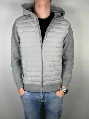 Reiss  - Snygg grå hoodie med quiltad, vadderad front och mjuka ärmar i sweatshirtmaterial. Dragkedja framtill och två sidofickor med zip. Stor huva och ribbade muddar. Perfekt för en chill och stilren look.