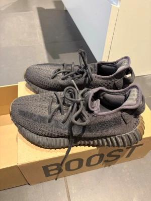 Svarta Yeezy cinder Boost 350 V2 sneakers - Säljer ett par svarta Yeezy cinder Boost 350 V2 sneakers från Adidas. Säljer dp jag ahe växt ur dem och därmed inte avänder dem. Har använt dem en del men fortfarande bra skick, det enda en att ena skons snöre har 