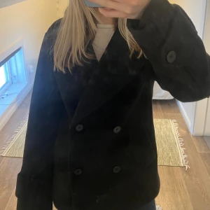 Svart dubbelknäppt rock - Snygg svart rock med dubbelknäppning och bred krage. Klassisk modell med stora knappar och rak passform. Perfekt för dig som vill ha en stilren och tidlös look. Passar till många olika outfits och är enkel att matcha. knappt använd och köpt nyligen🩷
