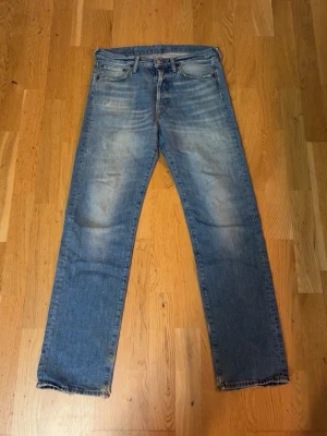 Blå raka jeans med slitningar från Acne studios  - Säljer ett par klassiska blå jeans med raka ben och diskreta slitningar på framsidan. Jeansen har fem fickor och en ljus tvätt med vintagekänsla. Materialet är denim och passformen är relaxed. Perfekt för dig som gillar en avslappnad stil.