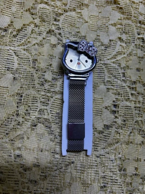 Hello Kitty klocka med meshband - Snygg klocka från Hello Kitty med/ett meshband i metall och urtavla formad som Hello Kittys ansikte. Klockan har en glittrig rosett och finns i både silver och guld. Perfekt accessoar för dig som gillar söt och snygg design. Nya klocka med nya batteri , 189kr/st 