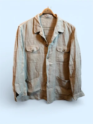 Beige linneskjorta overshirt från Matinique  - Stilren beige overshirt från Matinique i luftigt linne. Skicket är grymt och overshirten passar till allt och är perfekt för sommaren. Storlek är L men passar större. Perfekt lager på lager-plagg för en avslappnad men snygg look. Vid fler frågor är det bara att höra av er!
