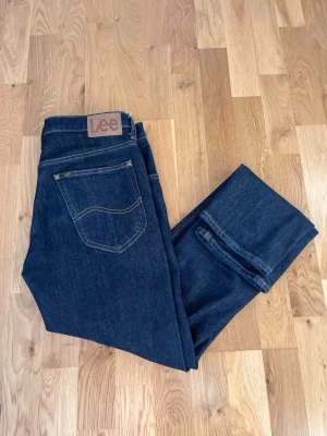 Mörkblå Lee Daren jeans W31 L32 - Säljer ett par mörkblå Lee Daren jeans med klassisk femficksdesign och brunt Lee-märke på bakfickan. Säljer pga att dem är för små för mig. Jeansen har dragkedjegylf och är tillverkade i bomull med en snygg, tidlös passform. Perfekta för dig som gillar stilrena och bekväma jeans. Använda enbart någon vecka bara. Lätt att styla med!