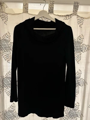 Svart långärmad polotopp - En svart långärmad polotopp från MOM By Lindex med en mjuk och stretchig känsla. Toppen har en klassisk polokrage och är perfekt för lager-på-lager. Enkel och stilren design som funkar till många olika looks.